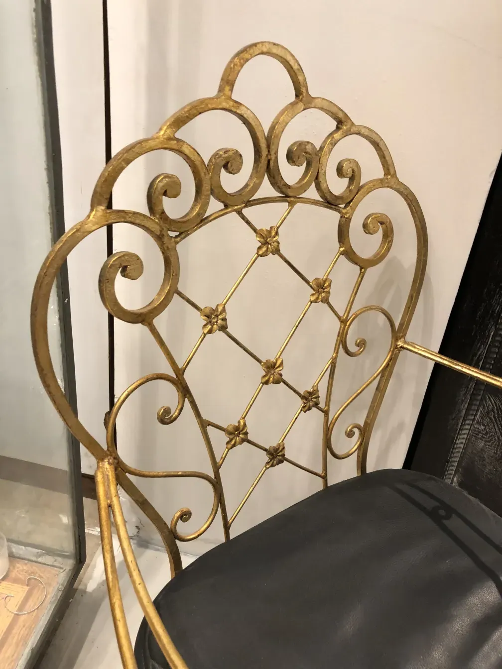 Vue de deux fauteuils de jardin anciens en fer forgé doré, entourés d'un cadre accueillant.