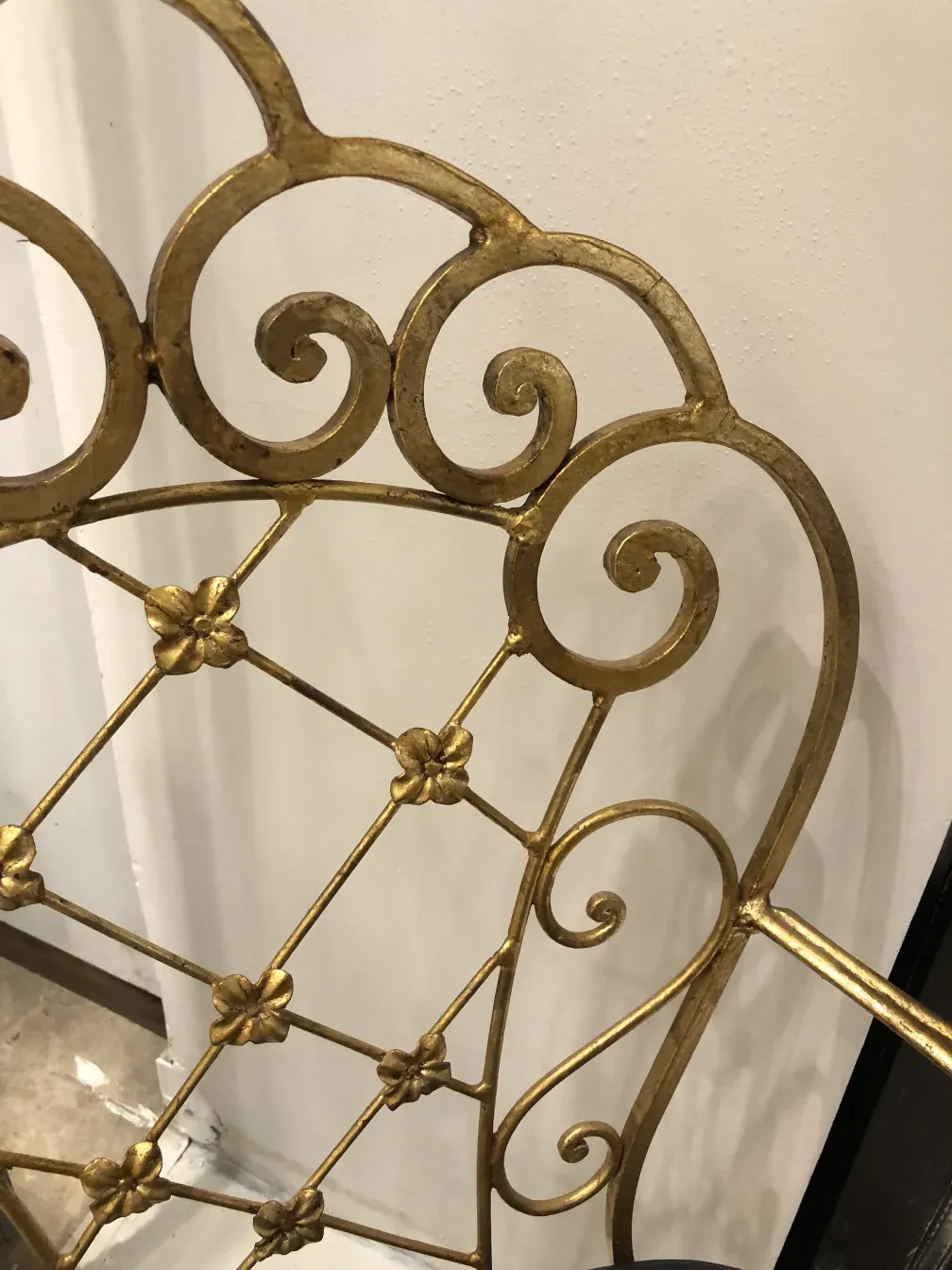 Detalhe de 2 poltronas de jardim antigas art deco com design intricado ao fundo.