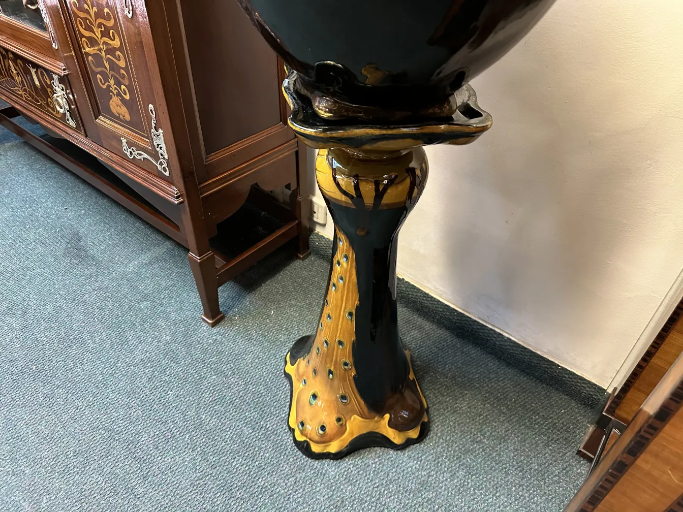 View of a decorative antique planter, featuring a base with yellow and blue details