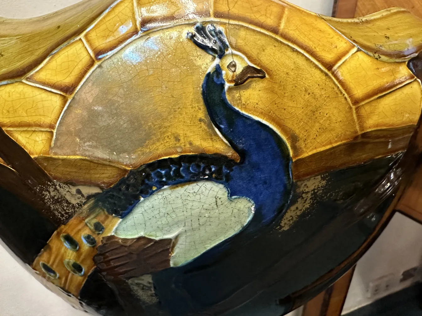 macetero antiguo decorado con un pavo real colorido en la superficie