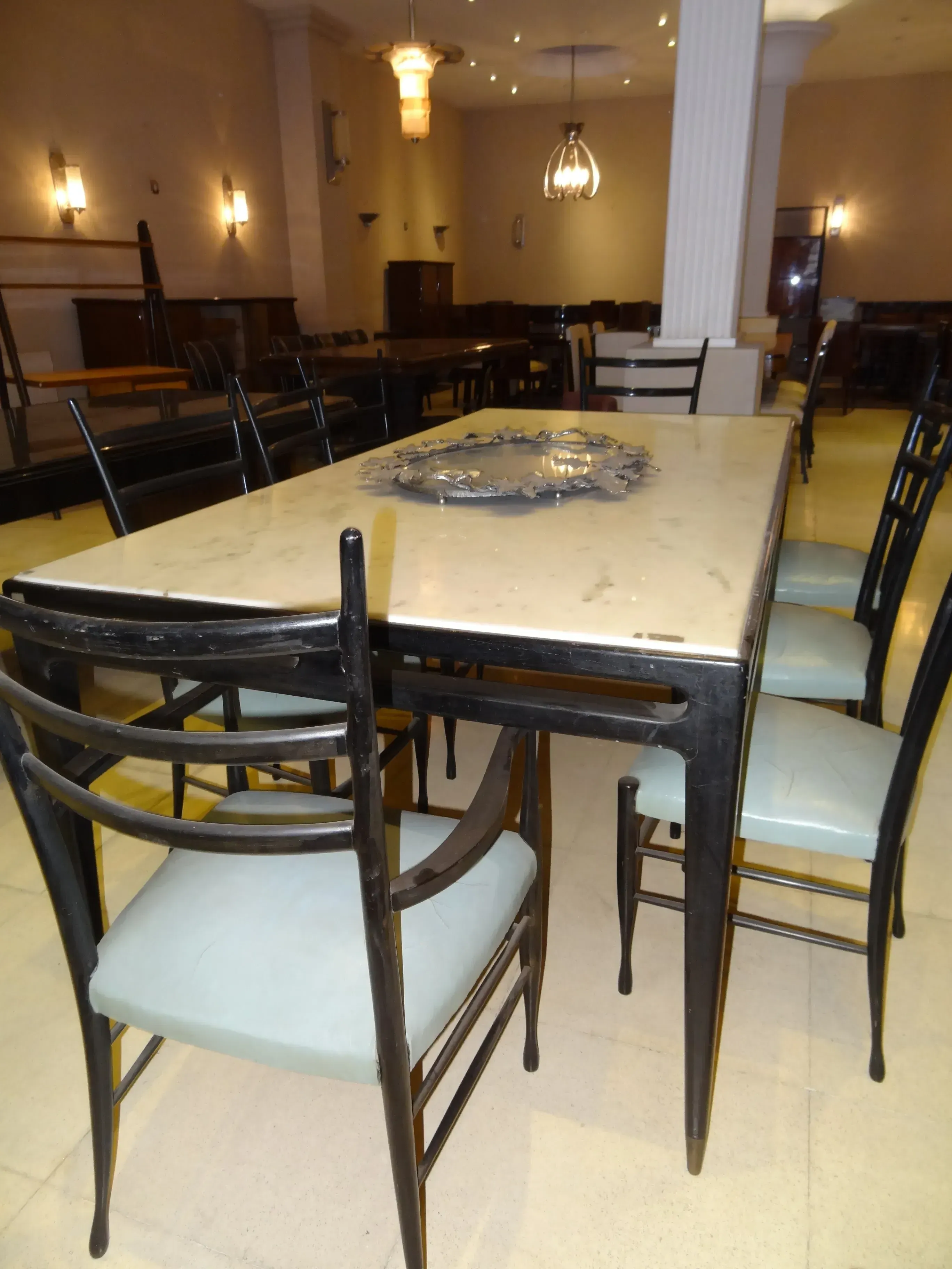 Mesa de jantar antiga de Gio Ponti para 8 pessoas, com cadeiras elegantes no ambiente.