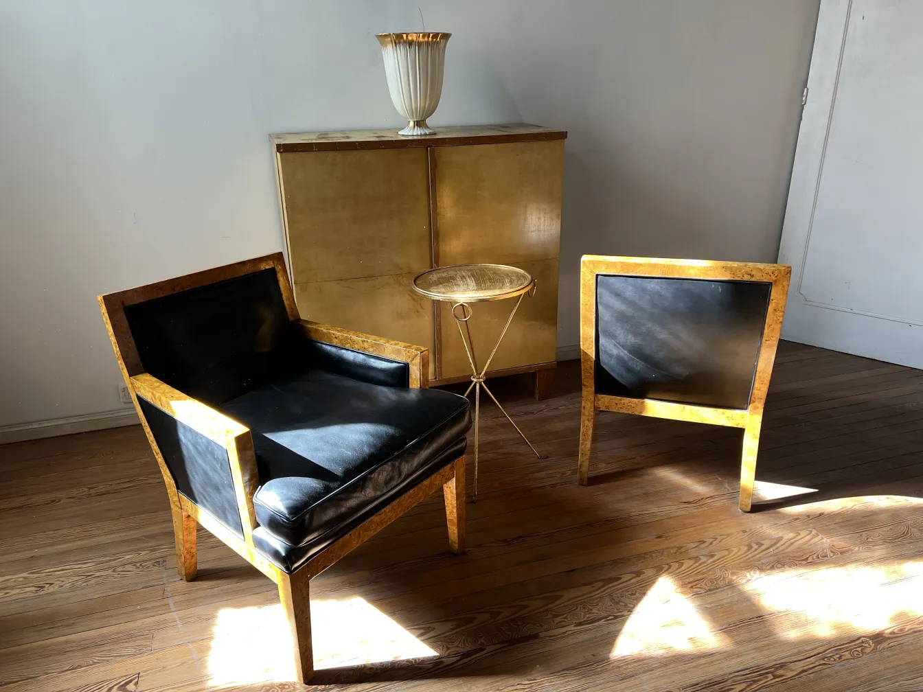 Deux fauteuils anciens au design distinctif dans le salon, l'un à côté de l'autre, avec une table dorée au milieu