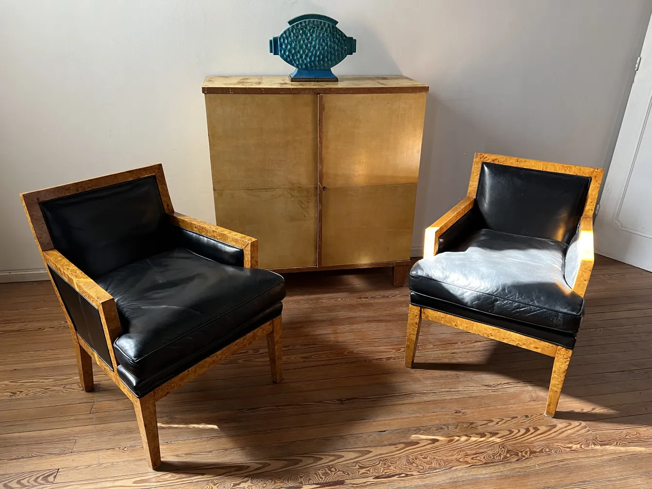 Two antique armchairs with elegant design and black details, in a modern setting.