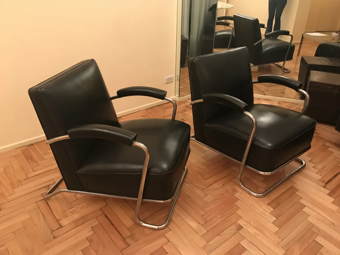 dos sillones antiguos art deco con brazos y base metalica, en un ambiente acogedor