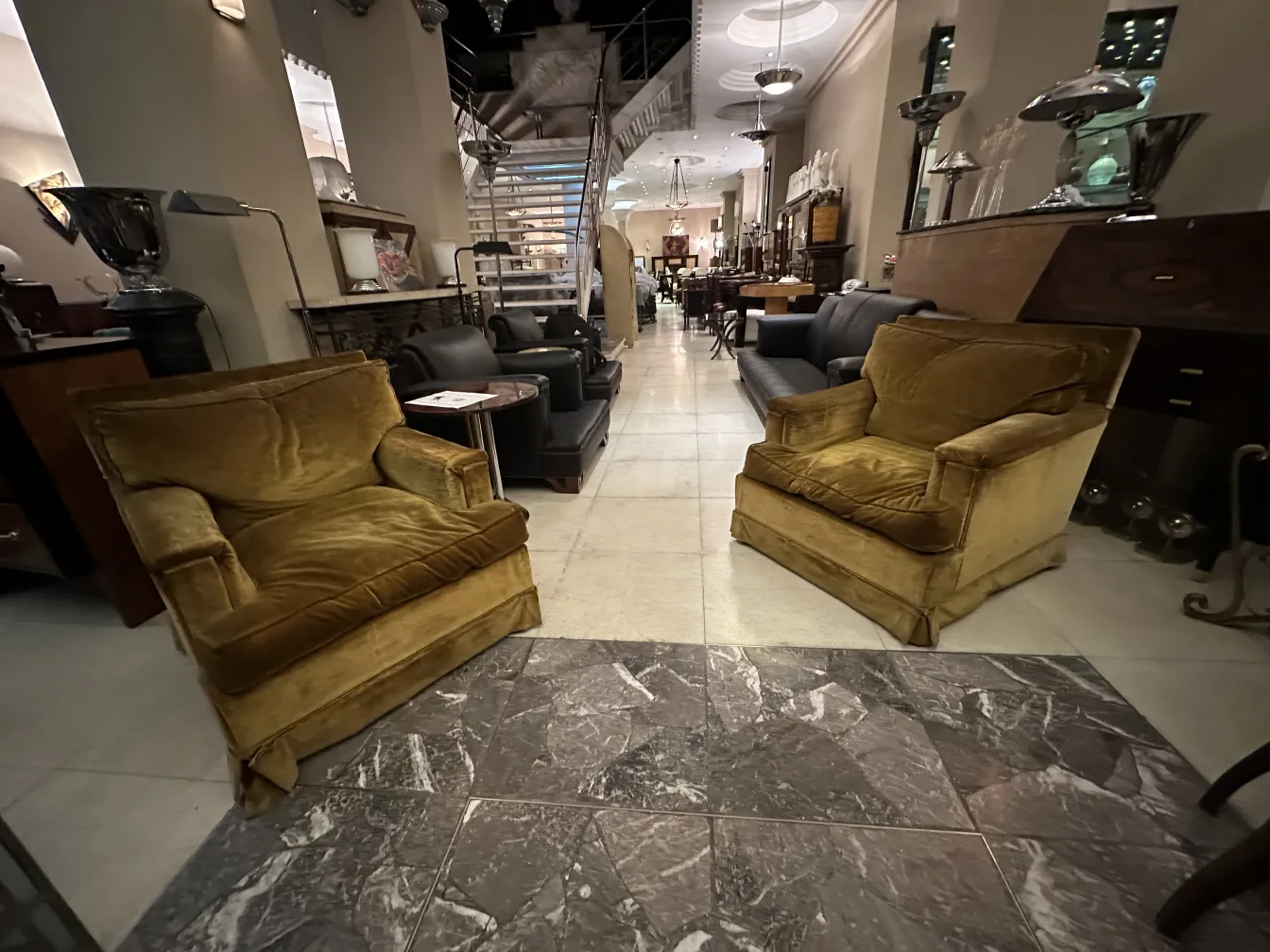 Two antique armchairs set in a stylish environment with various furniture around.