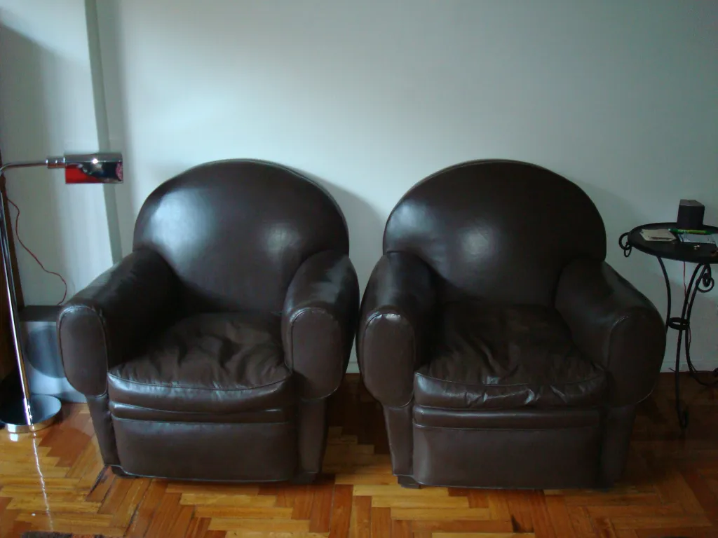 Two antique Ruhlmann armchairs needing restoration in a cozy setting.