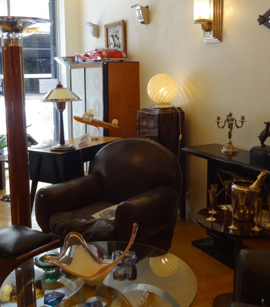 Deux fauteuils anciens avec des courbes douces et du tissu usé dans un décor élégant.