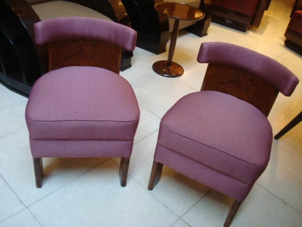 Two antique armchairs in a purple hue within a classic setting.