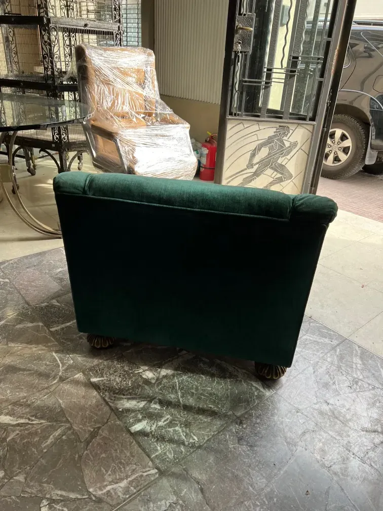 Duas poltronas antigas verdes prontas para serem restauradas em um ambiente acolhedor com outros móveis.