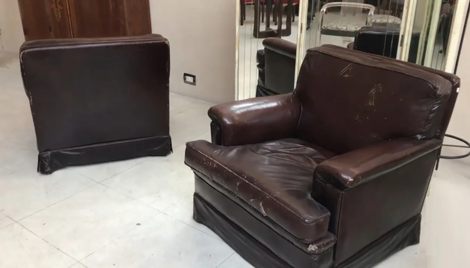 two worn antique armchairs facing each other in a room.