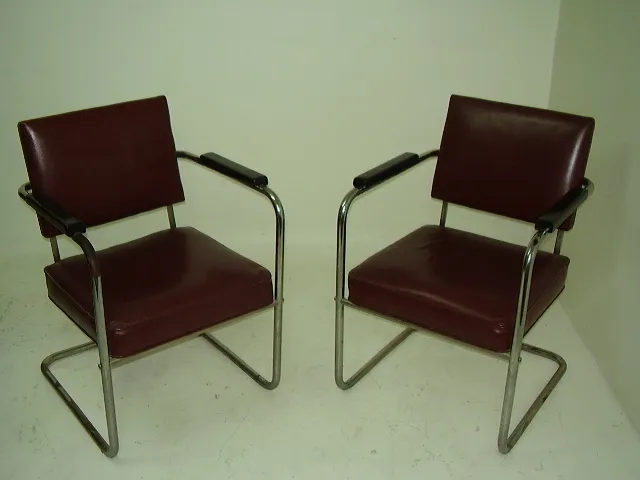 par de poltronas para serem restauradas em marrom, com braços, em um ambiente neutro.