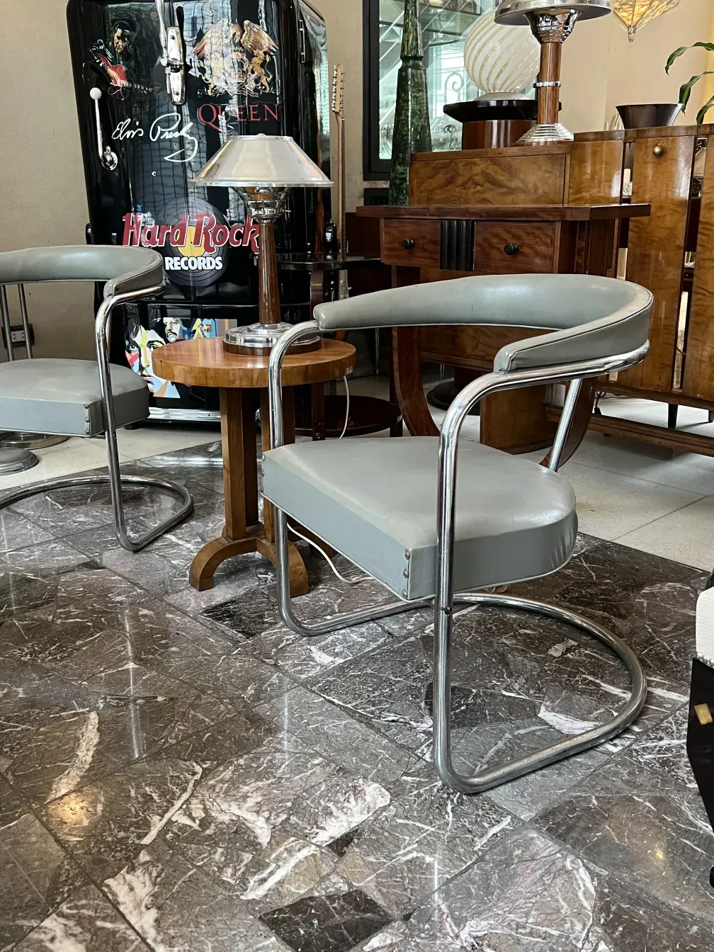 Dos sillones antiguos de diseño moderno para restaurar, con estructura de metal y tapizado claro, en un entorno vintage.