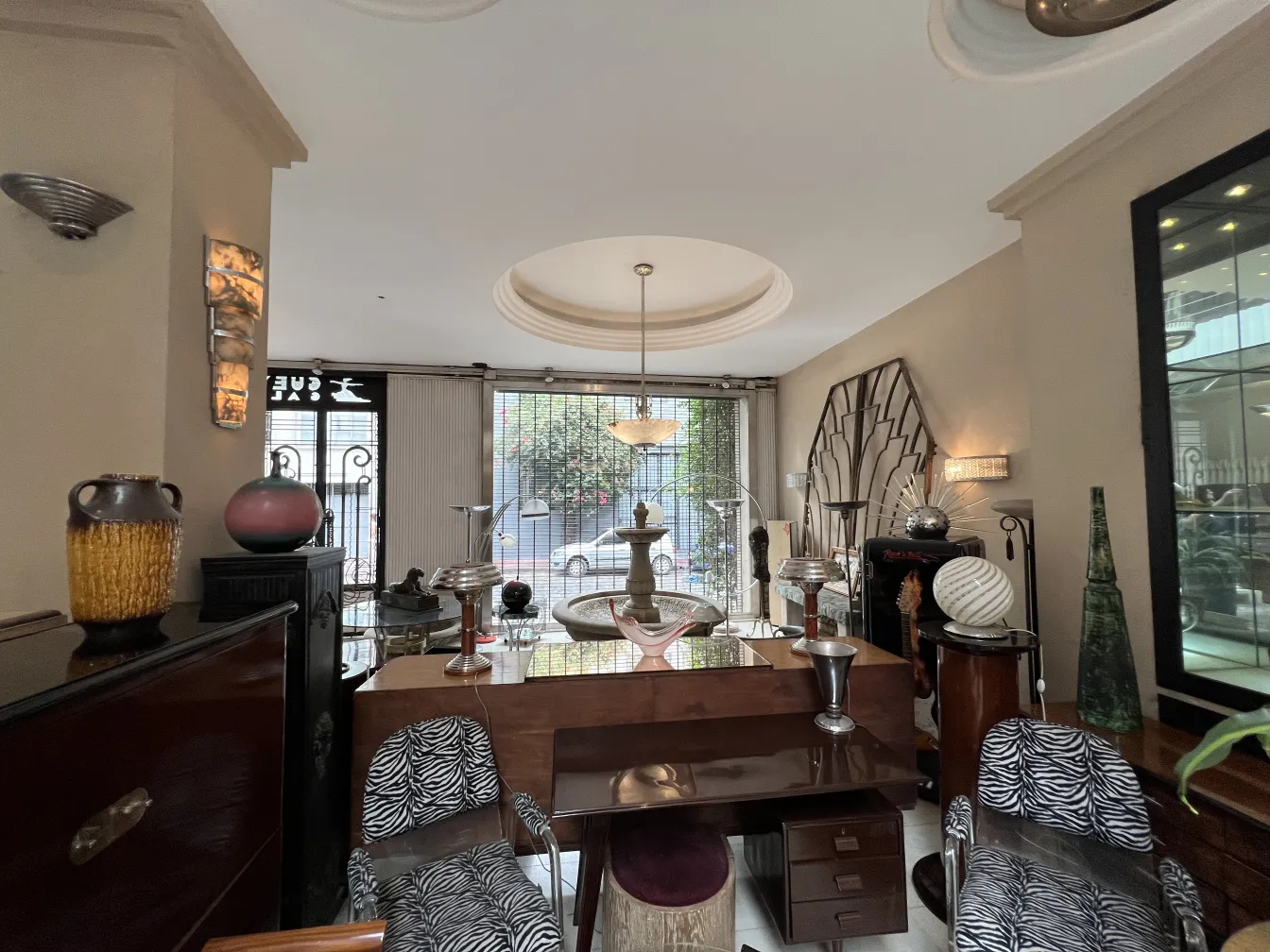 Zwei antike Armlehnstühle verschönern ein Wohnzimmer mit Vintage-Objekten wie Vasen und Lampen.