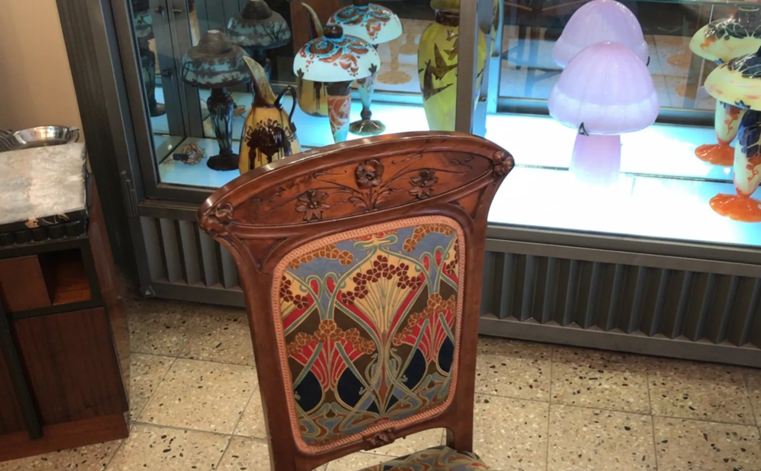 Silla antigua de estilo Art Nouveau con tapizado colorido y detalles decorativos.