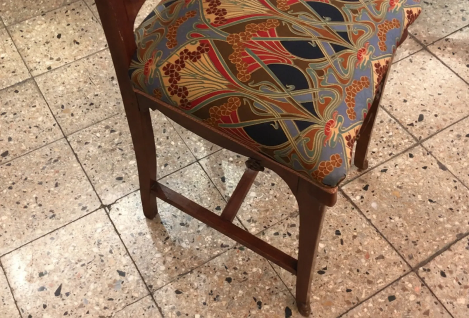 Sedia antica con motivo colorato in un ambiente di antiquariato.