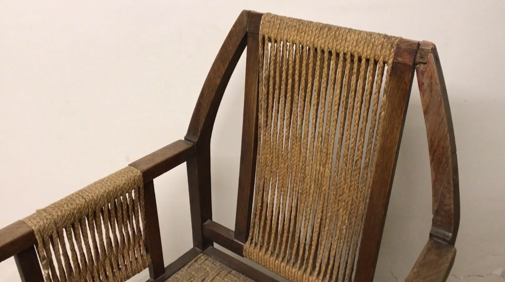 Sillón de escritorio antiguo con respaldo y brazos de cuerda.