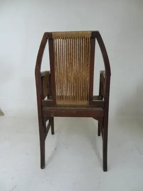Sillón de escritorio antiguo con respaldo de listones, ambiente sencillo.