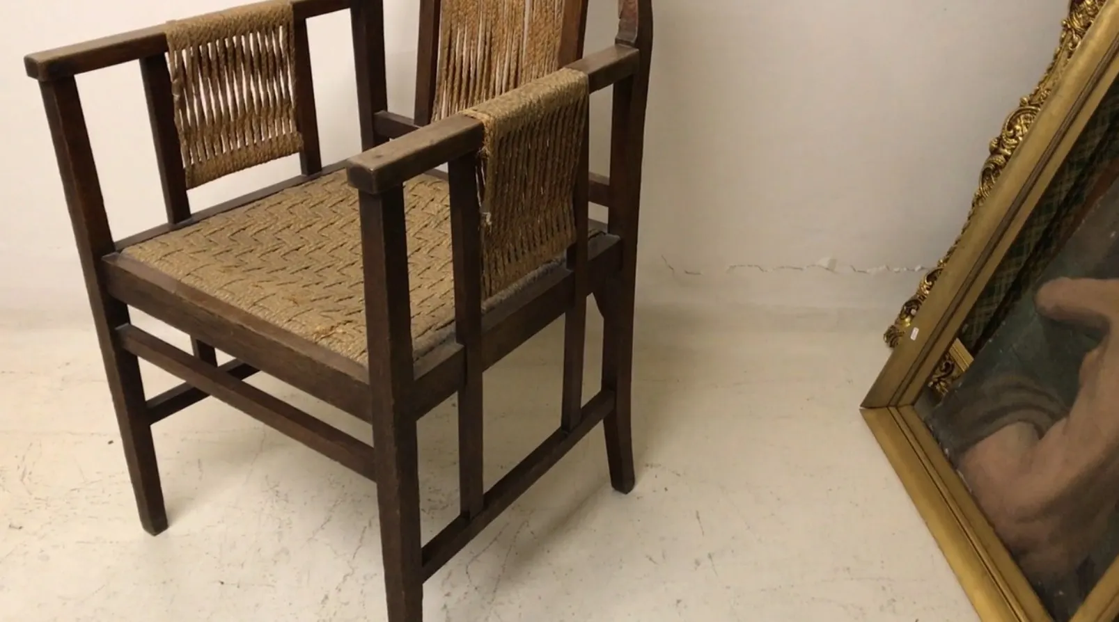 Antique desk chair with a woven seat design in a minimalist setting.