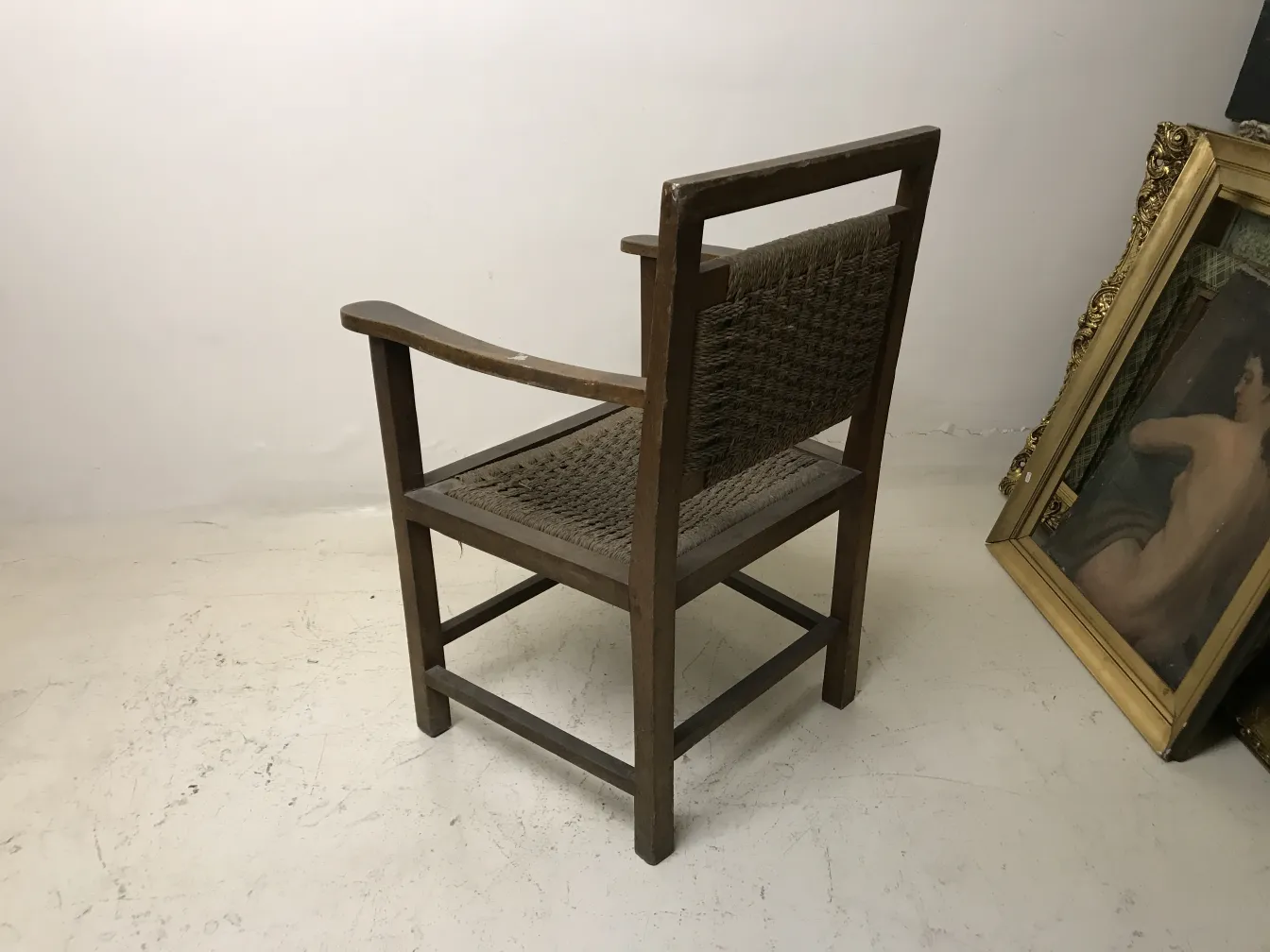 Fauteuil ancien avec accoudoirs et dossier tressé. Environnement artistique.