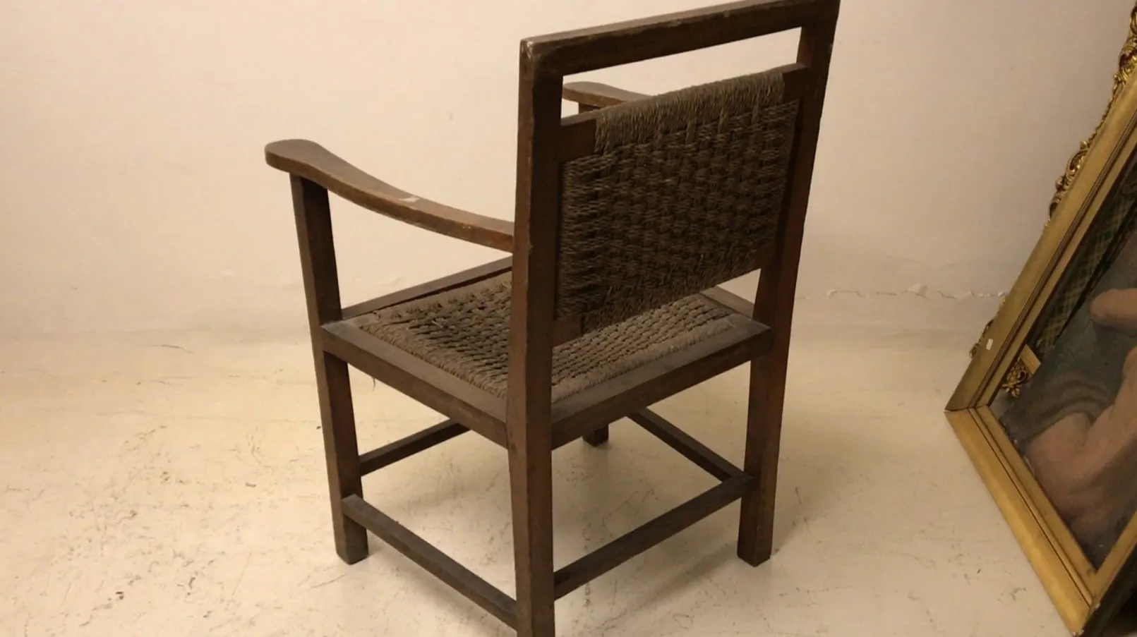 Poltrona antica in stile Art Nouveau con schienale alto e braccioli curvi in un ambiente semplice.