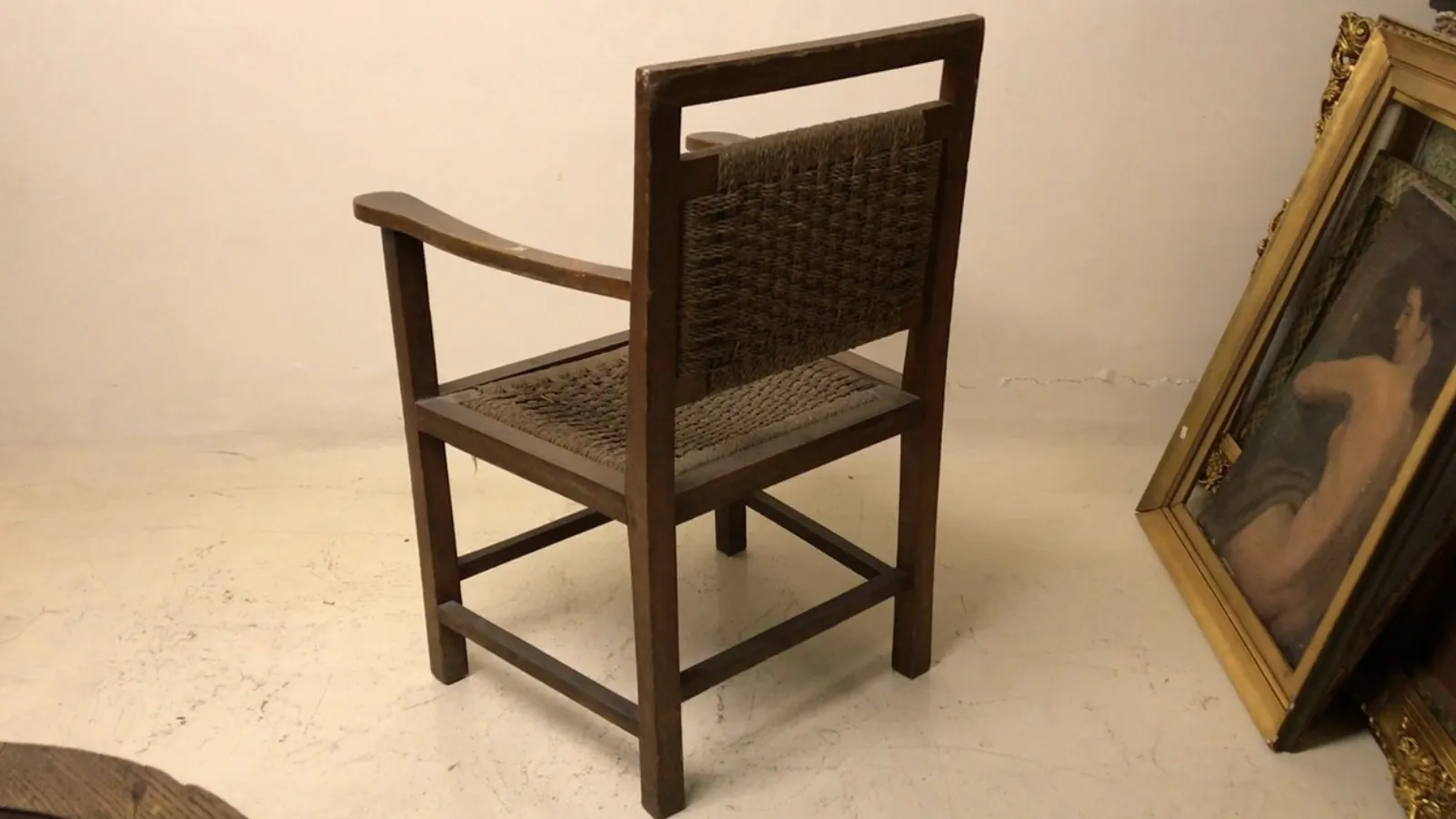 Fauteuil ancien de style Art Nouveau avec dos tissé, dans un environnement élégant.