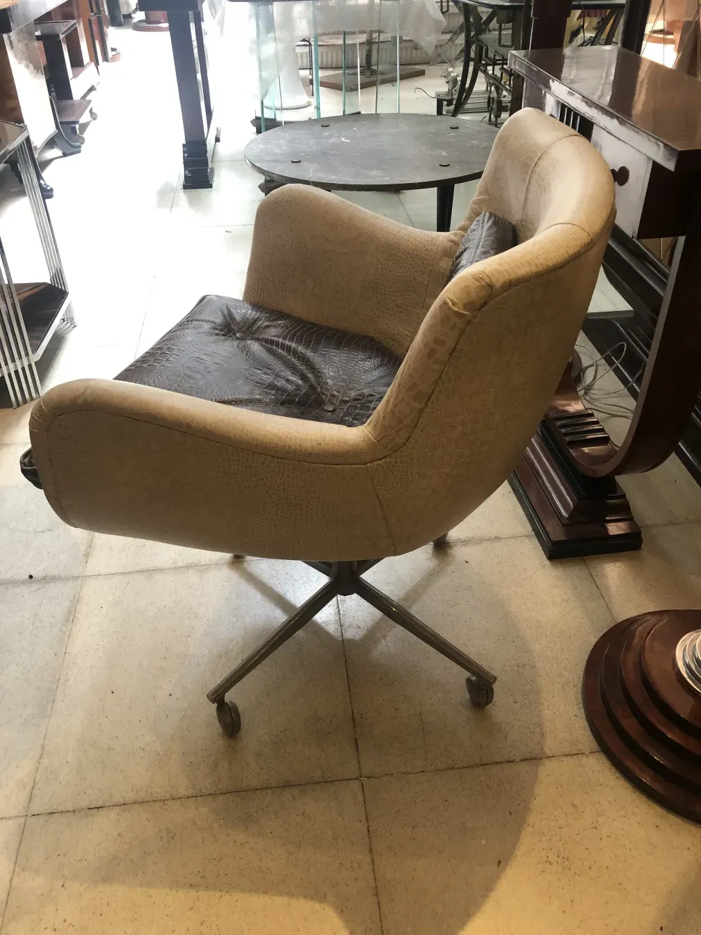 Weicher beiger antiker Sessel mit Rädern an der Basis.