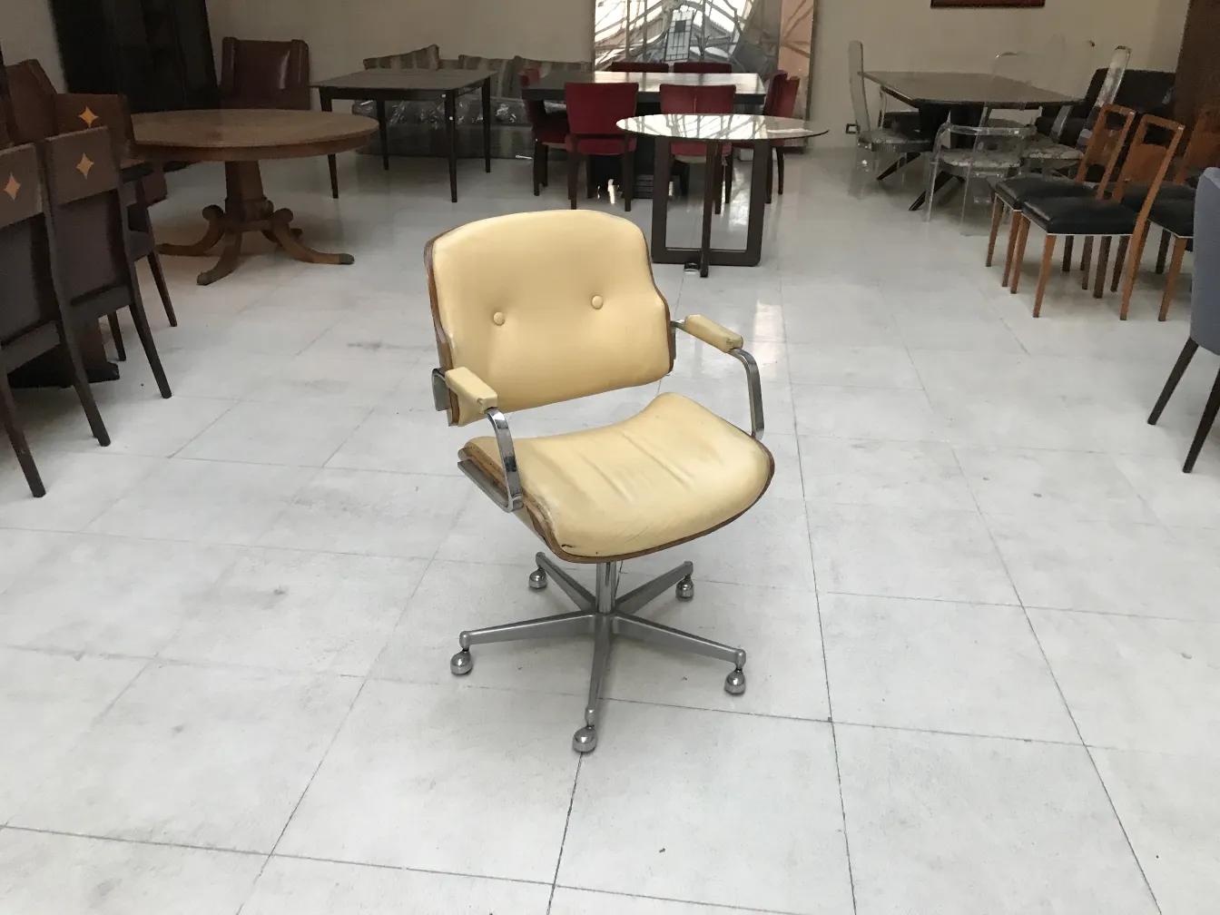 Cadeira de escritório antiga em um ambiente com mesas.