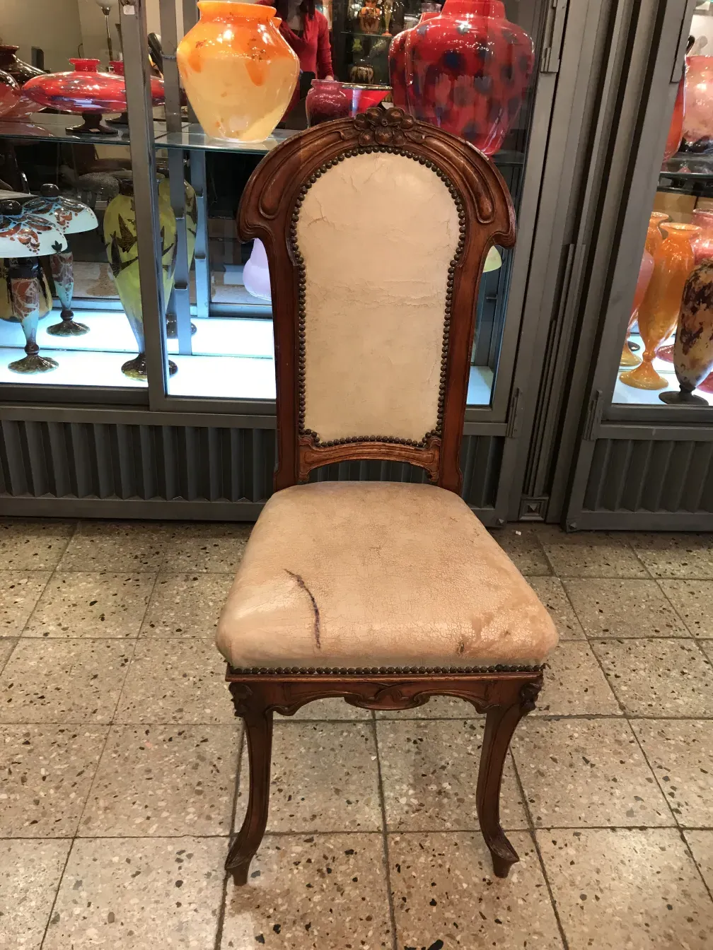 Antique chair with high back, art nouveau style, surrounded by decorative objects.