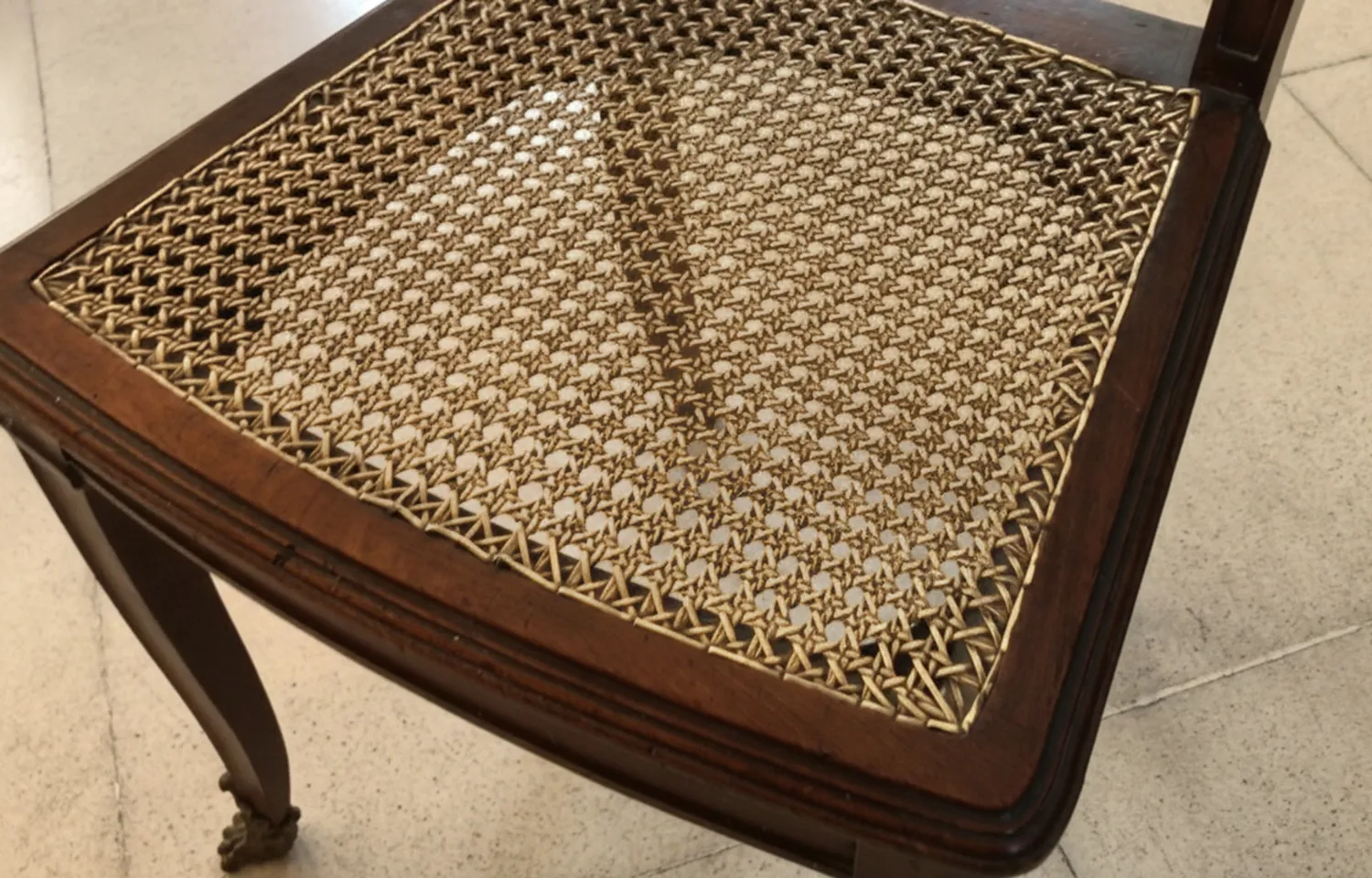 Close-up view of 2 antique chairs with intricate details in a classic setting.