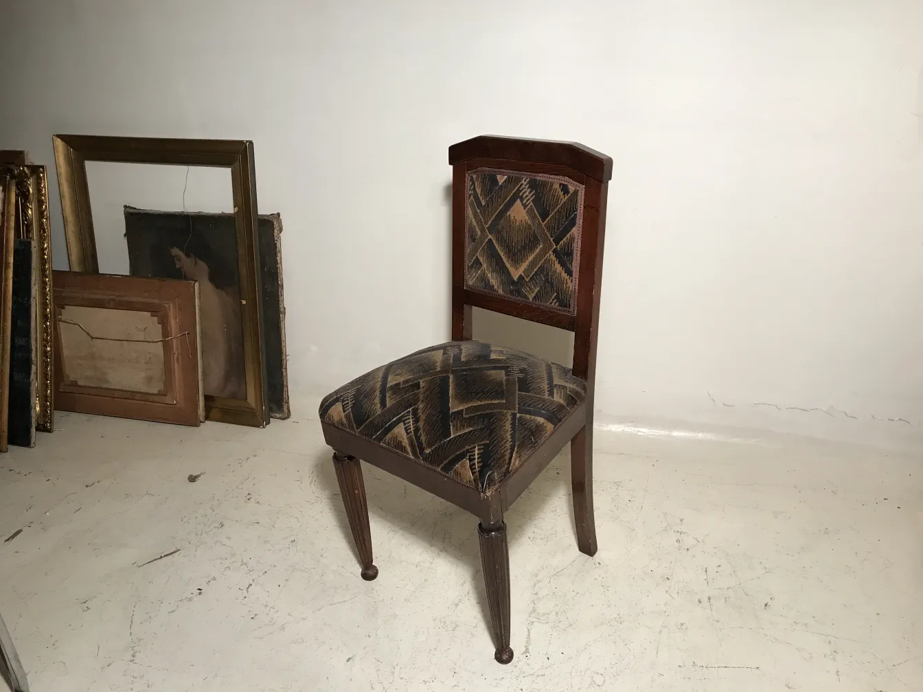 Dos sillas antiguas con diseño distintivo en un ambiente vintage, una incompleta en restauración.