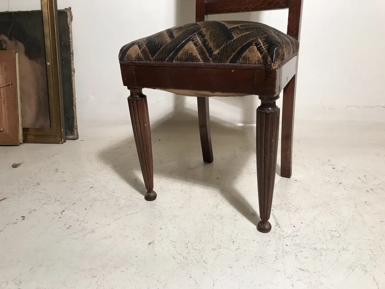 Deux chaises anciennes avec des pieds tournés et un tissu décoratif.