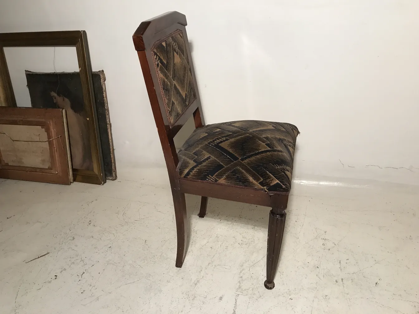 Two antique chairs with patterned upholstery, neutral background.