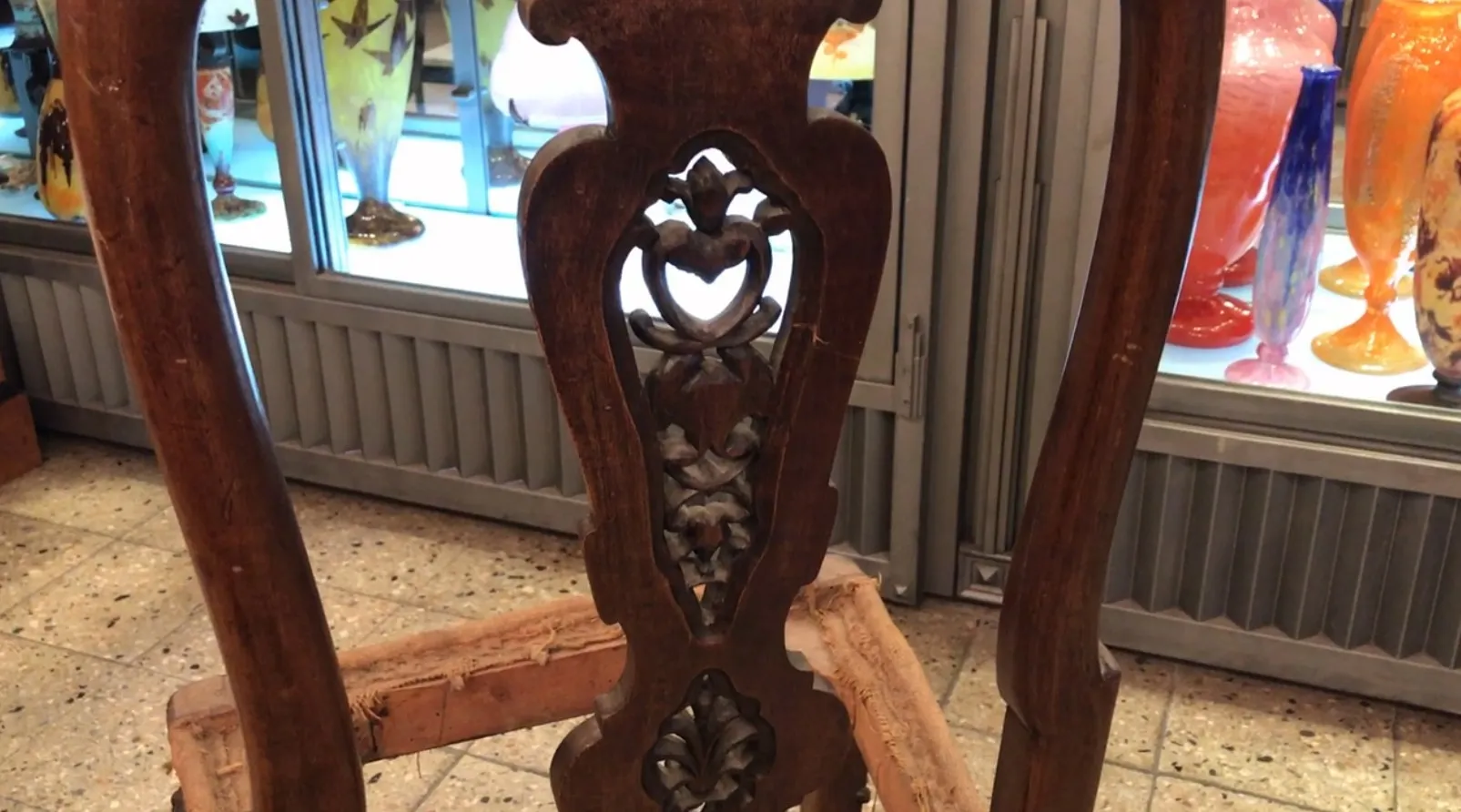 2 antique chairs for restoration with intricate carvings, background with colorful vases.