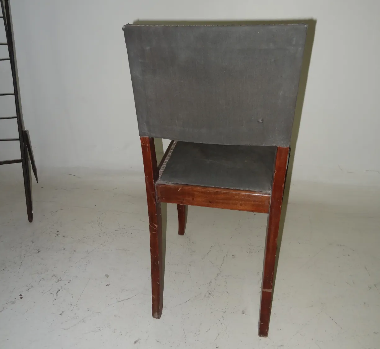 chaise ancienne avec dossier recouvert de gris dans un cadre neutre