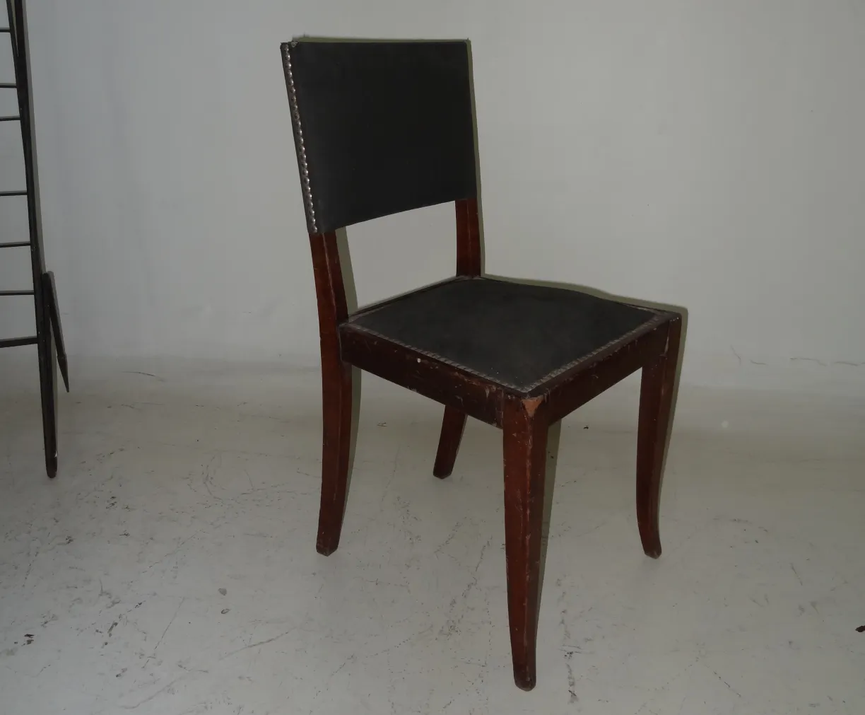 Side view of an antique chair with black upholstery, simple surroundings.