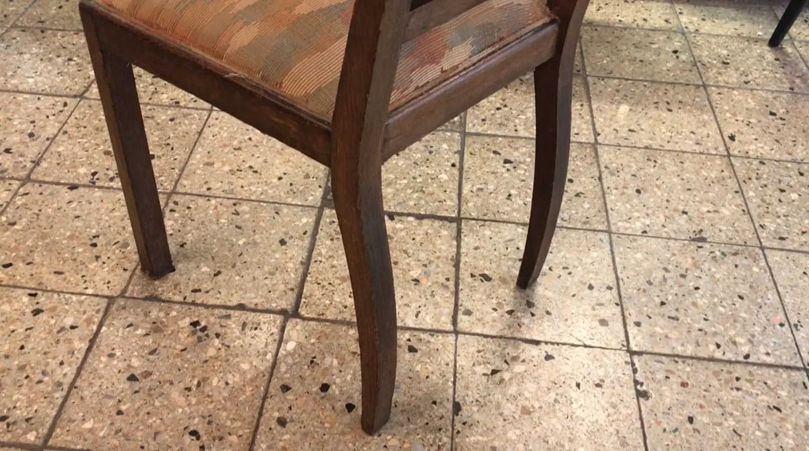 sedia antica in un ambiente neutro, con design classico. Pavimento in pietra.