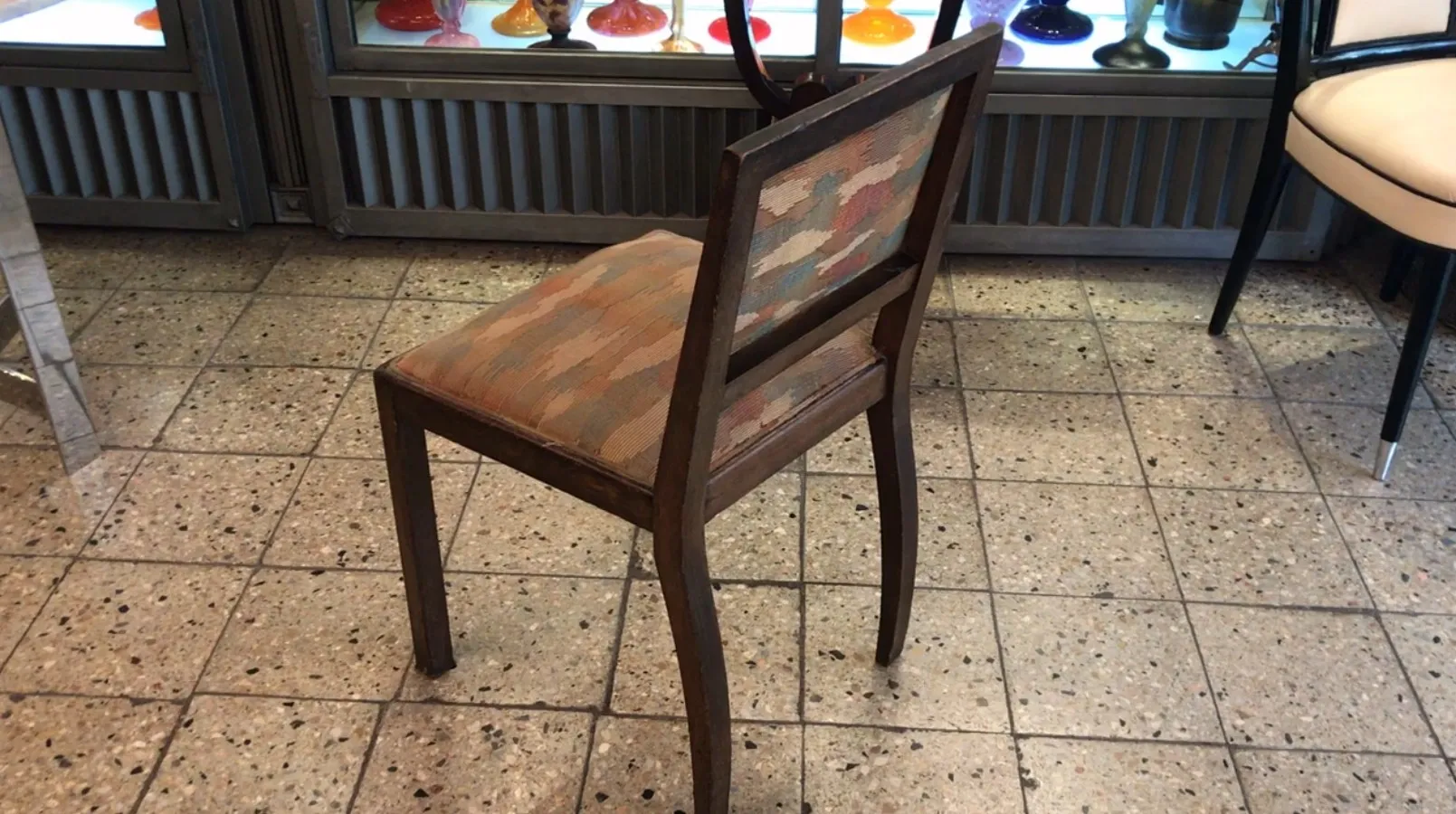 Silla antigua con respaldo decorado, en un ambiente colorido.