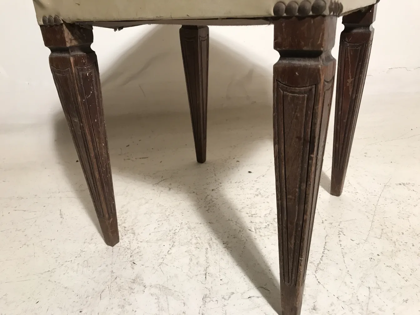 banqueta antiga com pernas decoradas e estofamento claro, ideal para decoração