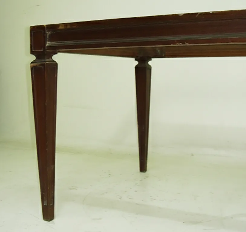 Antigua banqueta de pie con patas esculpidas en un entorno claro.