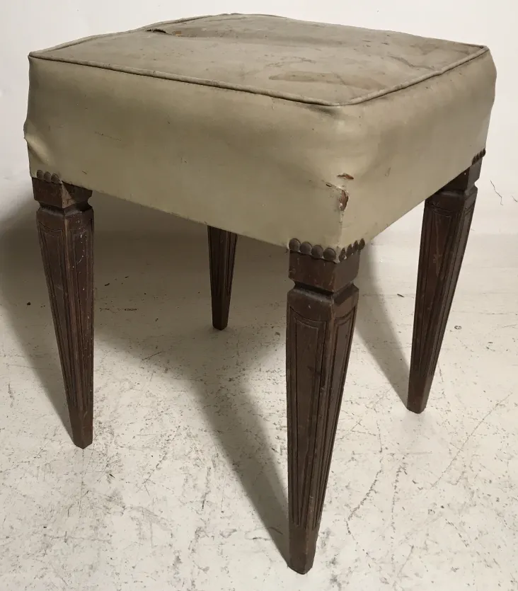 banqueta antigua con asiento tapizado en un entorno neutro