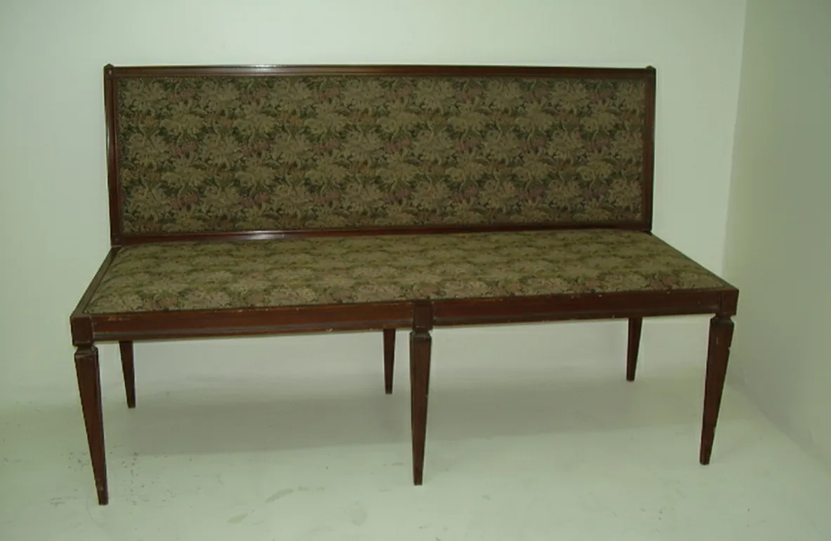 Ancien tabouret avec dos décoratif dans une ambiance neutre.