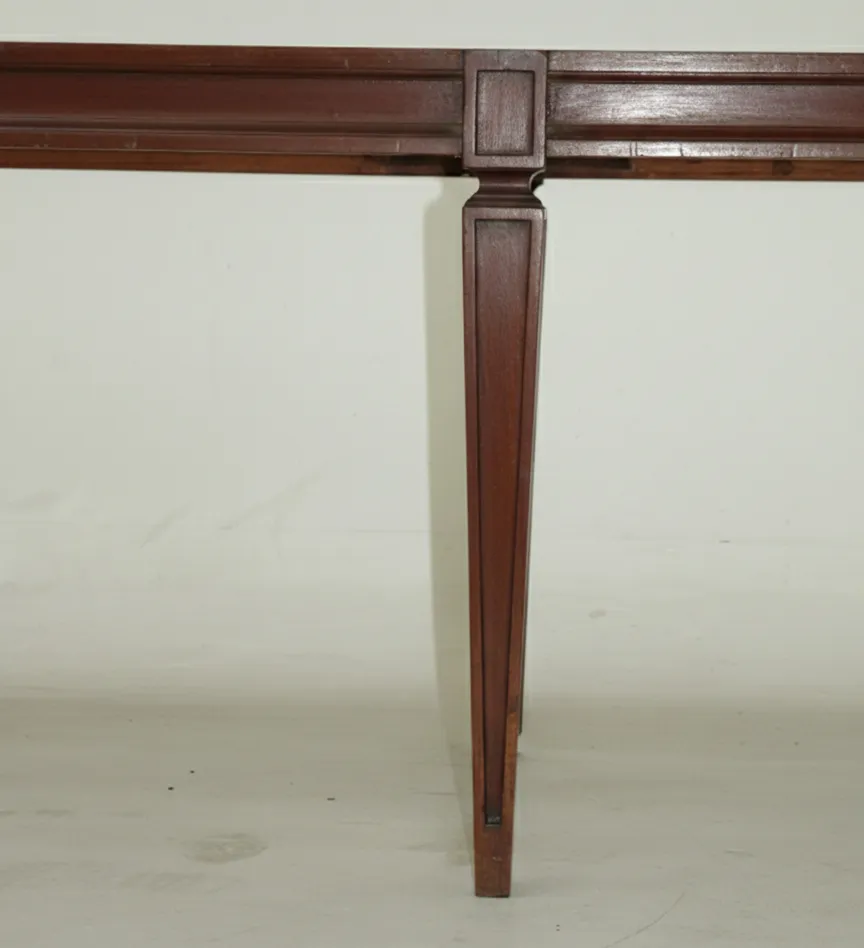 Antiga banqueta com pernas estruturadas em fundo neutro.