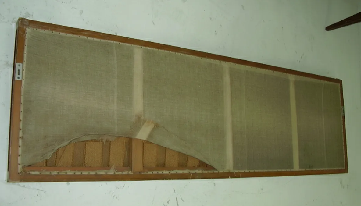 Antiker bequemer Hocker mit beschädigter Struktur in einem Vintage-Umfeld.