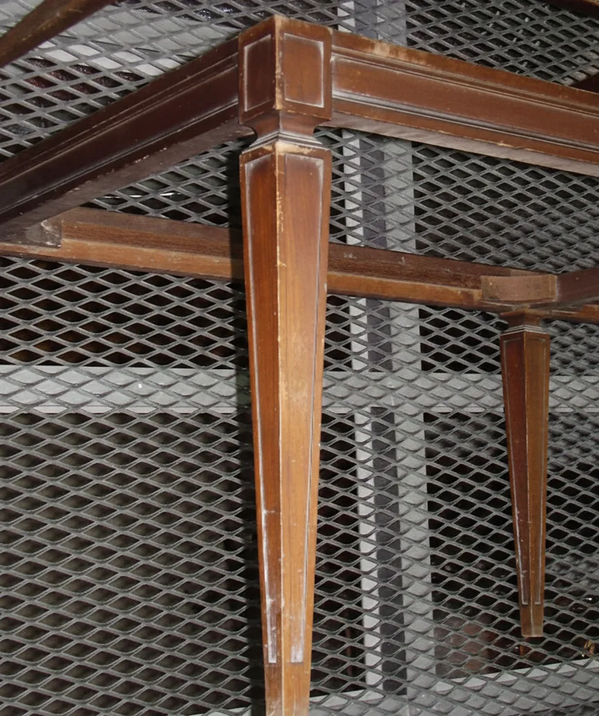 Antiga banqueta com pernas finas, fundo industrial.