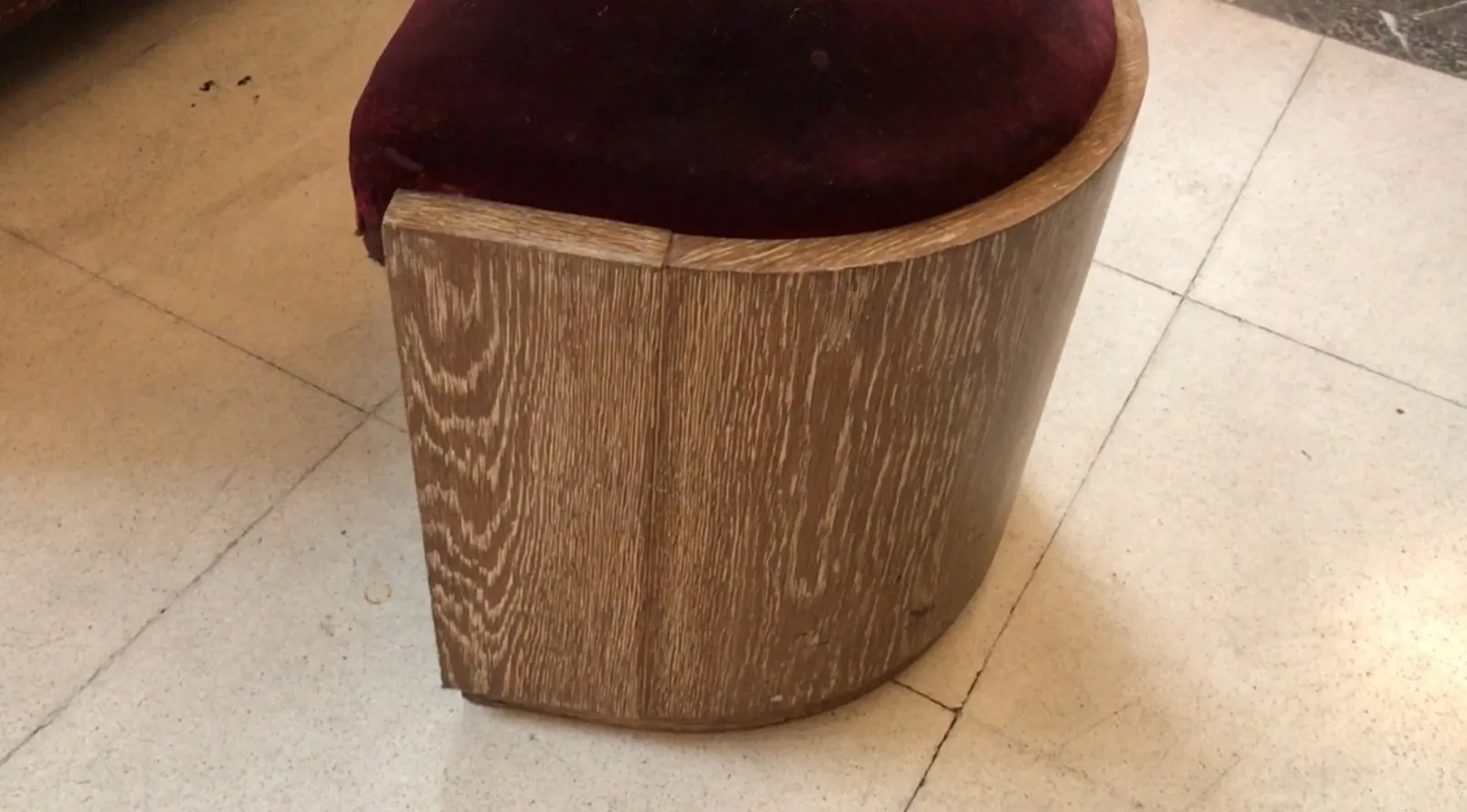 antique curved stool with padded seat, in a classic setting