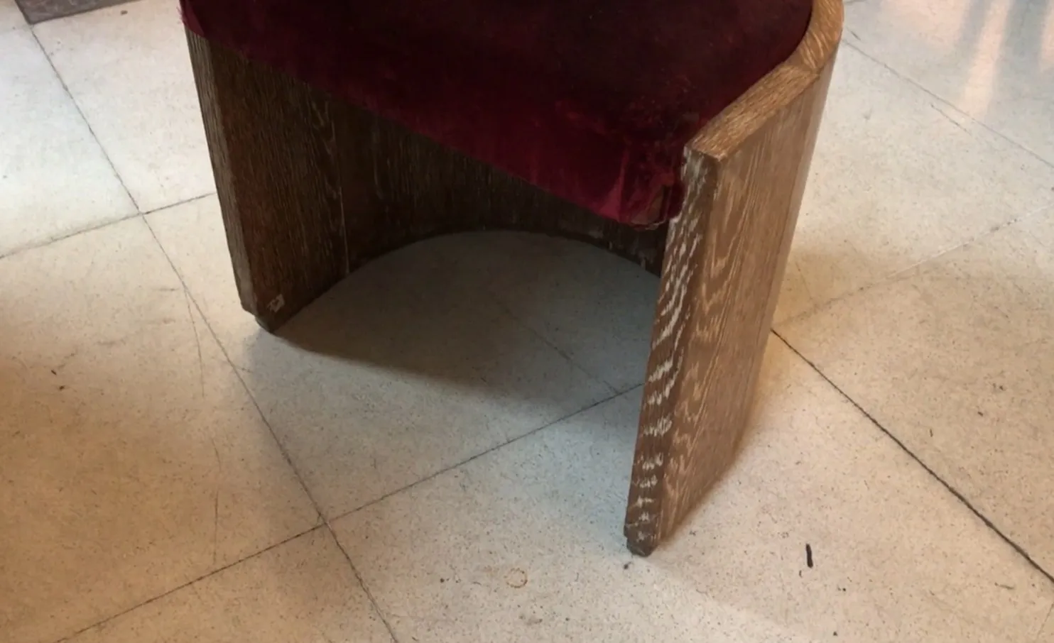 Sgabello antico con seduta in velluto rosso e design semplice, atmosfera accogliente.