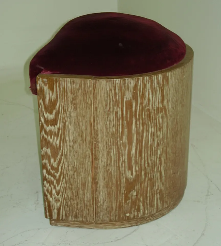 Antique stool with a round shape and burgundy upholstery.