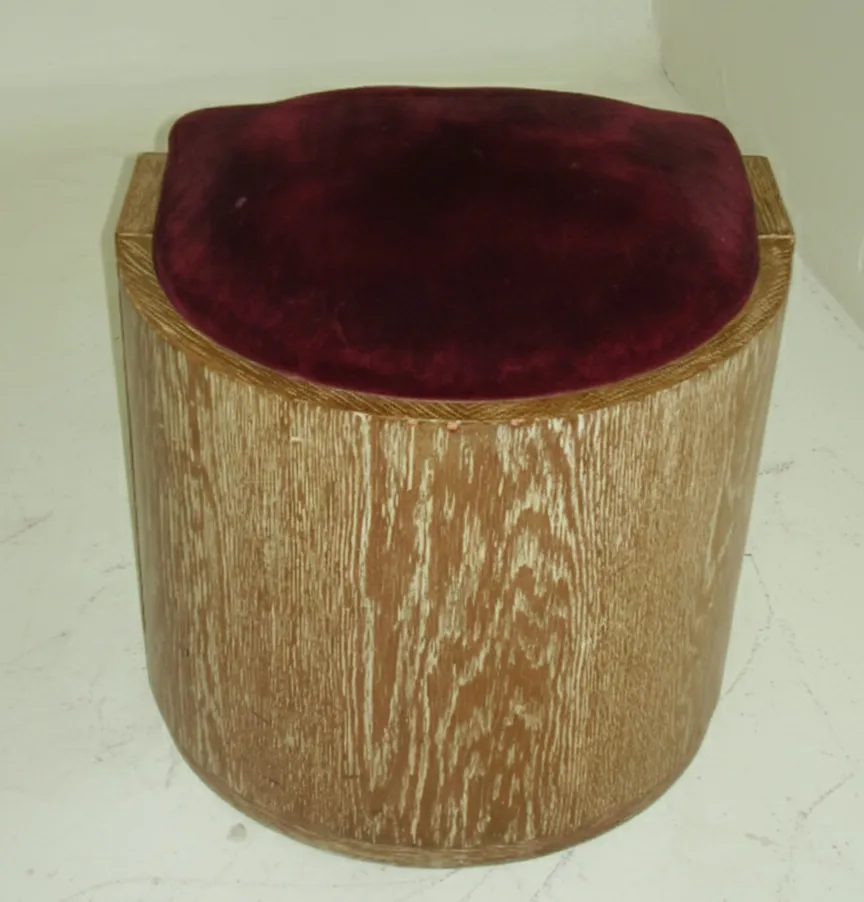 Tabouret antique rond, dans un cadre chaleureux avec un coussin bordeaux.