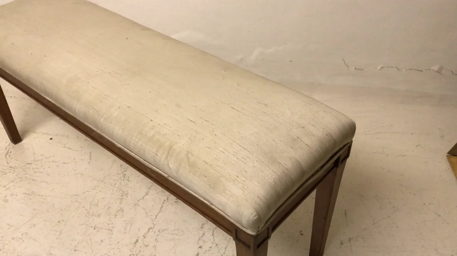 Antique bench with light cushion in a minimalist setting.