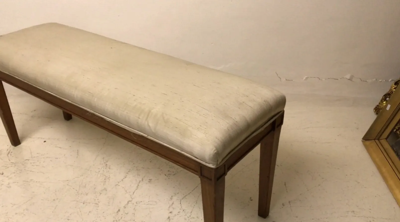 Antique bench with white seat and wooden legs, simple and elegant, set in a minimalist environment.